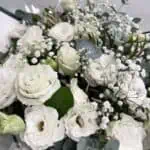 זר פרחים ליזי לבן הוא זר המבוסס על טהרת הצבע הלבן. שזור מפרחי ליזיאנטוס לבן, גיבסנית לבנה ואקליפטוס סילבר בשילוב ירק וענפי קישוט. הזר צולם מוחזק ביד על רקע הקיר בחנות.