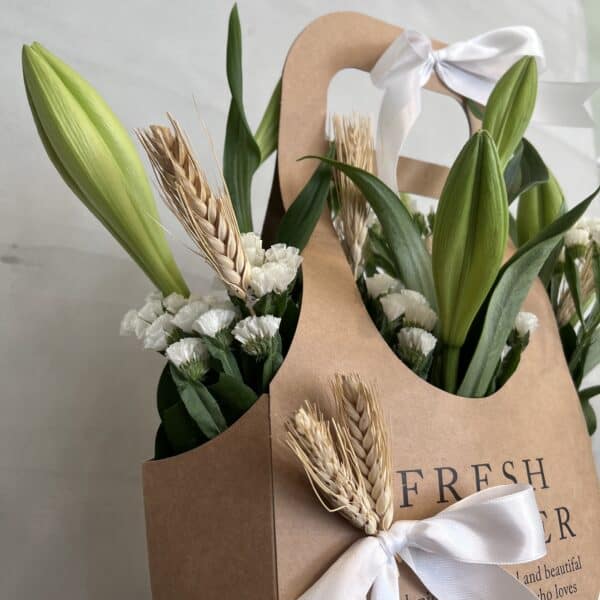 סל פרחים שושן צחור שזור מפרחי שושן צחור בשילוב ירק וענפי קישוט. תמונה על הקיר בחנות.