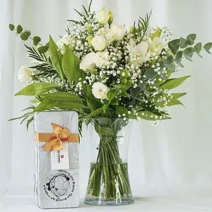 זר פרחים לבן שזור מפרחי שושן צחור, ליזיאנטוס לבן וגיבסנית לבנה בשילוב ירק וענפי קישוט לצד שוקולד קוואטרו.